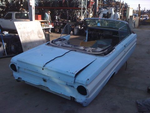 1964 Ford Ranchero - The rear of a light blue 1964 Ford Ranchero convertible body is seen in a junkyard setting.