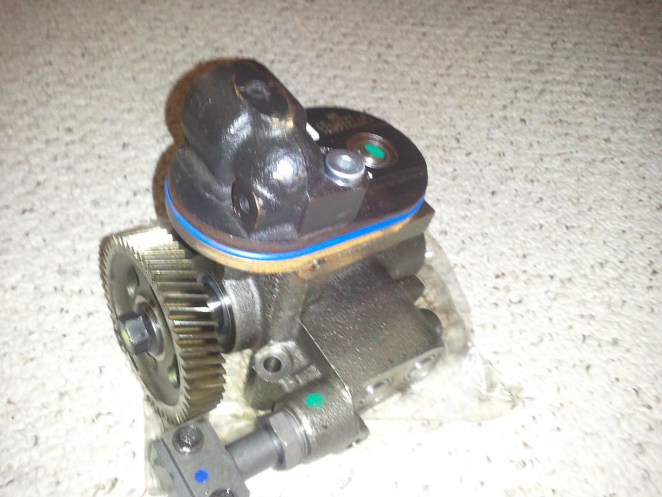 Black fuel injection pump with a silver gear and blue and green markings