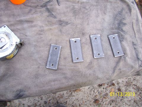 1990 Ford Bronco - Four metal brackets and a tape measure are shown on a cloth surface.