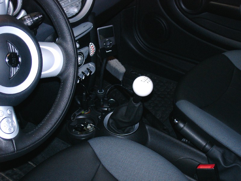 Interior of a MINI Cooper showing steering wheel, manual gear shifter, and handbrake.