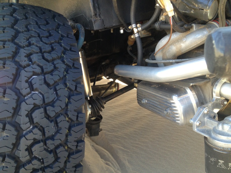 Close-up of off-road tire and engine components including a silver valve cover and exhaust pipe