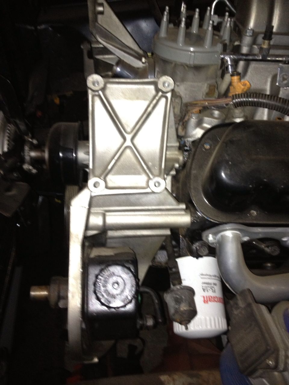 Close-up of engine component with oil filter and power steering reservoir