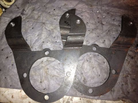 1994 Ford Bronco - Two metal brackets are shown, likely for a vehicle's braking system, on a textured surface.