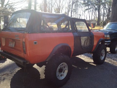 1994 Ford Bronco - An orange and black International Harvester Scout II is parked next to another vehicle.