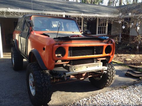 1994 Ford Bronco - This orange SUV, likely an International Harvester Scout, is missing its headlights and grille and sits high on large off-road tires.