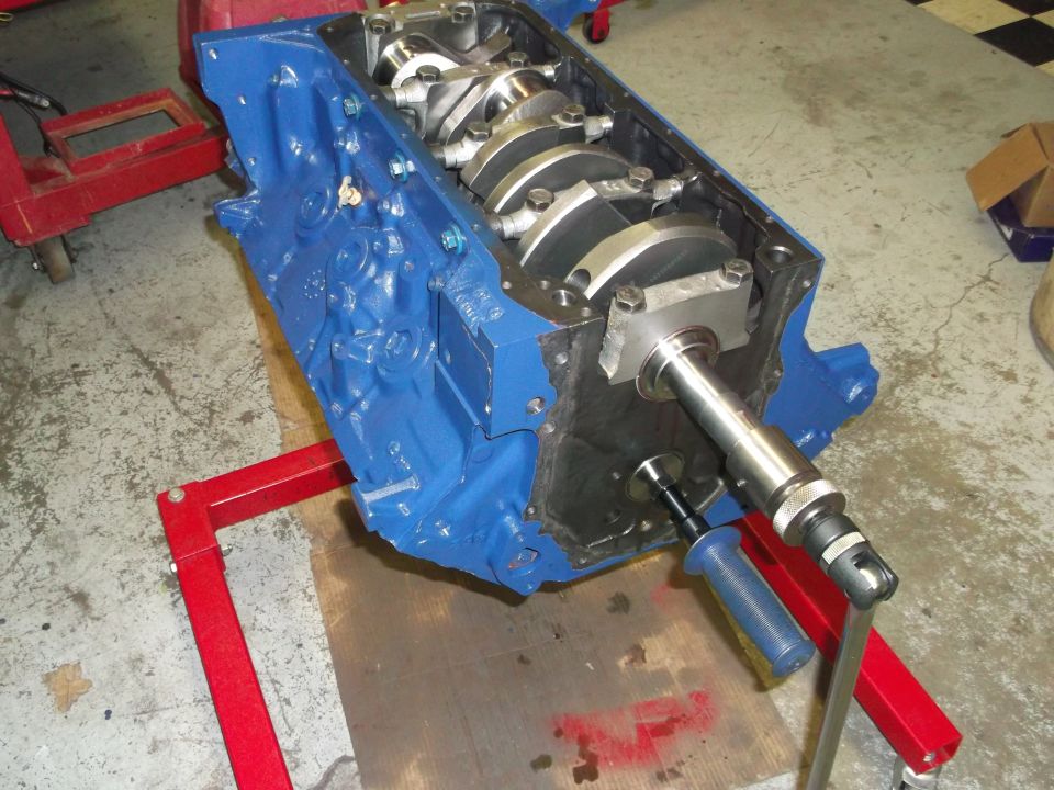 Blue engine block on red stand, showing crankshaft and bearings