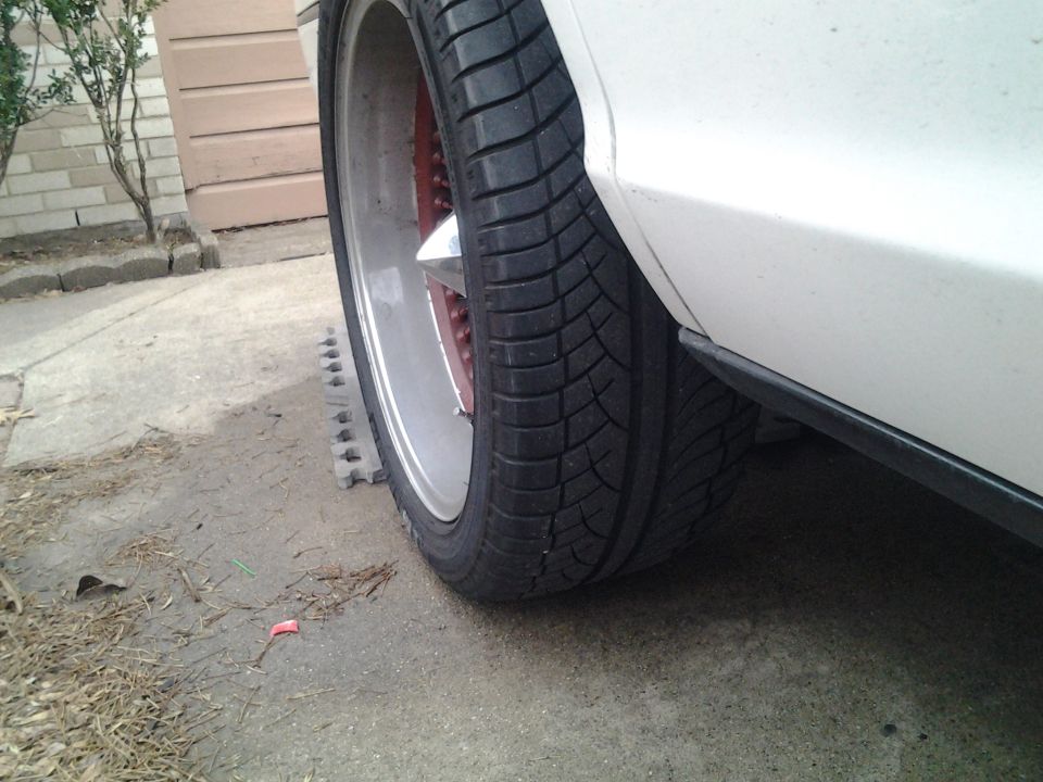 White car rear wheel with custom rims and low-profile tire, side view