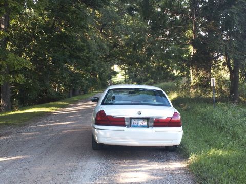 2000 Mercury Grand Marquis - A white 2000 Mercury Grand Marquis is seen from the rear on a gravel road surrounded by trees.