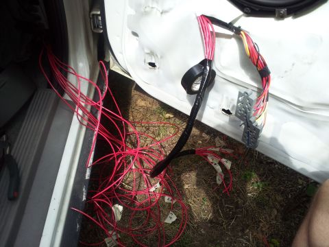2000 Mercury Grand Marquis - A car door's interior is exposed, revealing a complex network of red wires and electrical components.