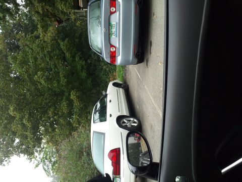 2000 Mercury Grand Marquis - A white 2000 Mercury Grand Marquis is parked next to a silver sedan on a cloudy day.