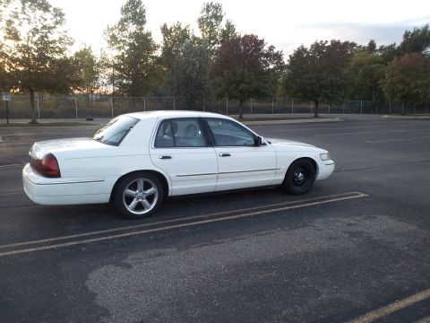 2000 Mercury Grand Marquis - White four-door Mercury Grand Marquis full-size sedan shown in side profile with black steel wheels, parked in an empty lot at dusk.