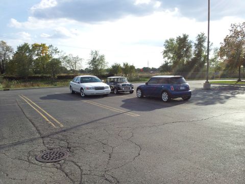 2000 Mercury Grand Marquis - Three cars are parked in a lot on a cloudy day.