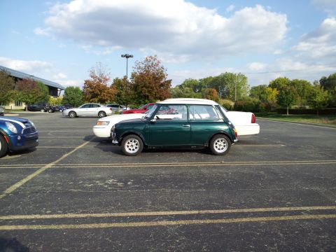2000 Mercury Grand Marquis - A classic Mini Cooper is parked in a lot with other vehicles under a cloudy sky.