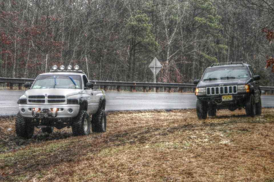 Silver Dodge Ram pickup truck and black Jeep Grand Cherokee parked on the side of a road.