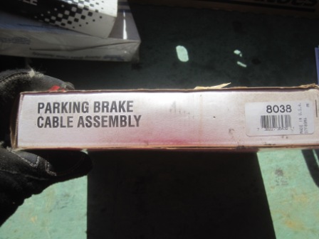 1993 Ford Bronco - A box for a parking brake cable assembly is held by a gloved hand.