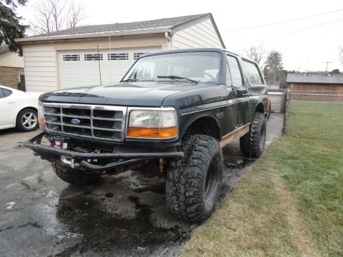 1995 Ford Bronco - This modified Ford Bronco sits parked in front of a suburban garage, ready for adventure.