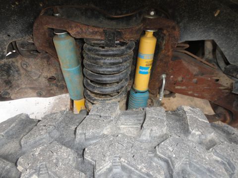 1995 Ford Bronco - Close-up view of the suspension system, a yellow Bilstein shock absorber and a coil spring.