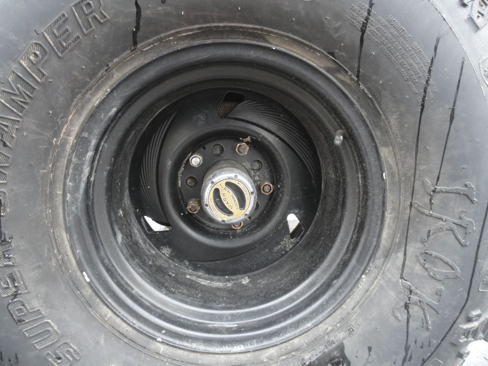 close-up of a vehicle's wheel and tire, showing a gold hubcap with text