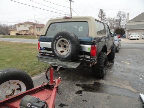 1995 Ford Bronco - Rear view of a 1995 Ford Bronco, showing the spare tire mounted externally and a trailer hitch assembly.