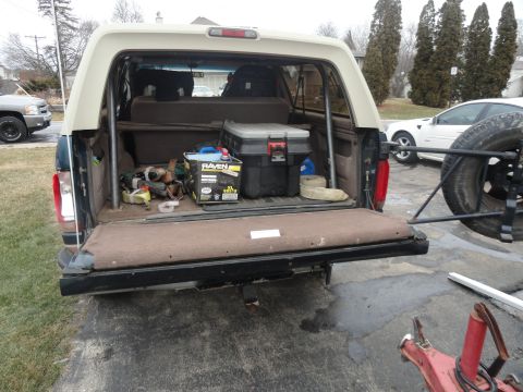 1995 Ford Bronco - Rear view of a 1995 Ford Bronco's cargo area, filled with tools and a spare tire.