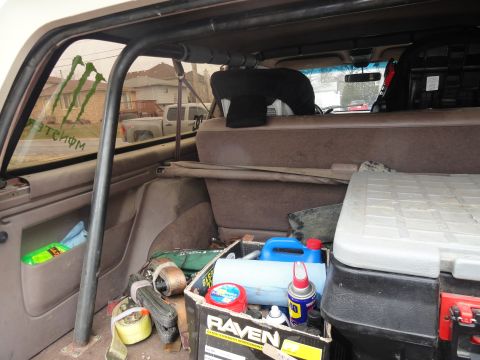 1995 Ford Bronco - The cargo area of the vehicle is filled with various items, including tie-down straps and a toolbox.