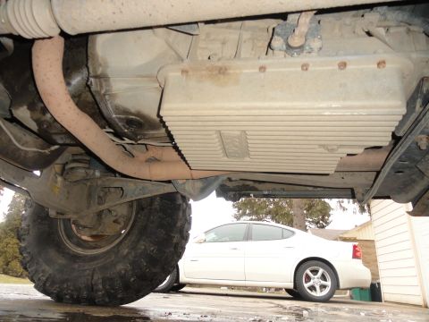 1995 Ford Bronco - Undercarriage of a vehicle with large tires, a white sedan is visible in the background.