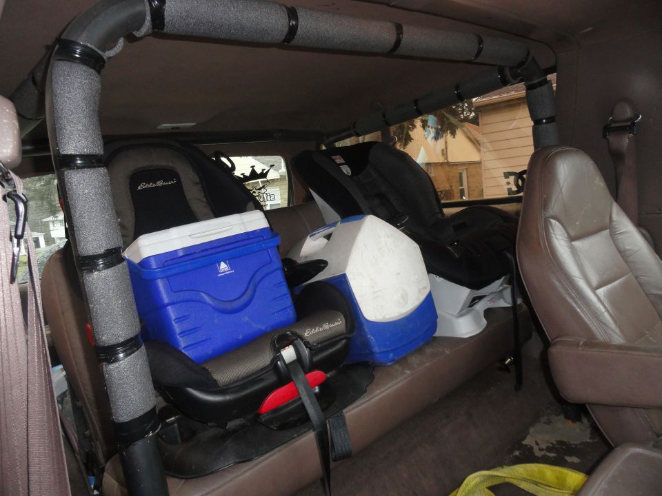 Interior view of a vehicle with two car seats and coolers on the back seat