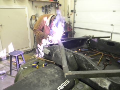 1990 Chevrolet Suburban - A person is welding a metal frame onto an ATV in a garage setting. The text 'ARIS' is visible on the ATV.