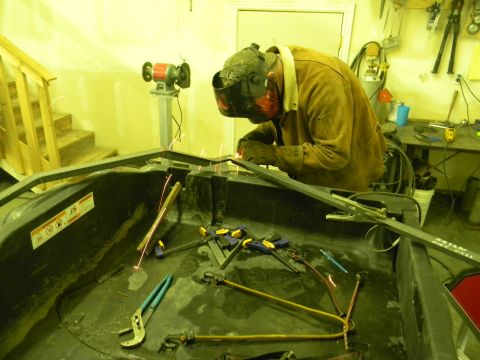 1990 Chevrolet Suburban - A person is welding a metal frame in a workshop with tools and equipment visible.