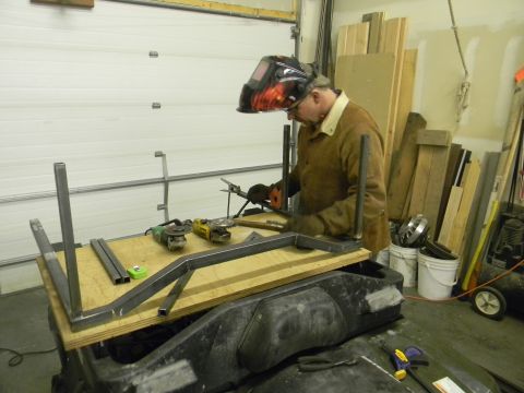 1990 Chevrolet Suburban - A person in welding gear works on a metal frame assembly placed on top of what appears to be an ATV body.