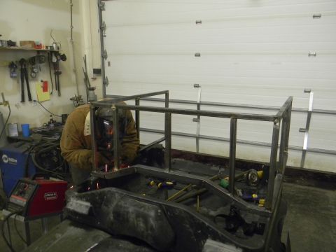 1990 Chevrolet Suburban - A person welds a custom metal rack onto the back of a utility vehicle in a workshop.