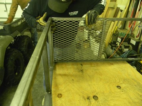 1990 Chevrolet Suburban - A person works on a metal frame structure next to a green ATV labeled "BIG BOSS".