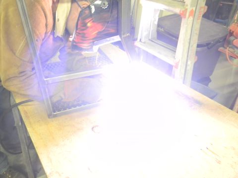 1990 Chevrolet Suburban - A person is welding a metal frame, creating a bright light.