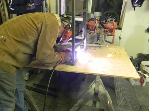 1990 Chevrolet Suburban - A person in a welding mask and protective clothing works on a metal structure in a workshop setting.