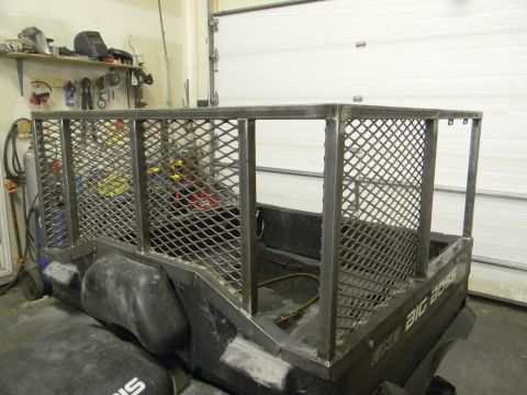 1990 Chevrolet Suburban - A utility vehicle with a custom metal cage is parked inside a garage with tools on a shelf in the background.
