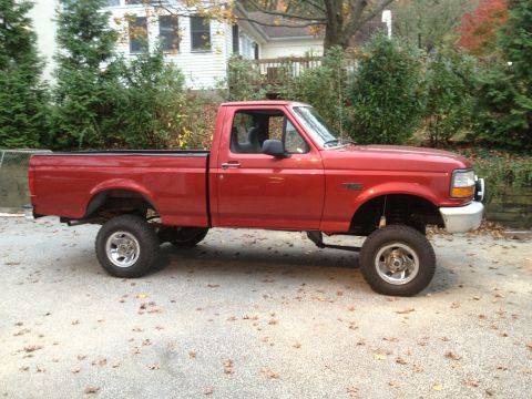 1996 Ford F-150 - A red 1996 Ford F-150 pickup truck is shown from the side, a lifted suspension and large tires.