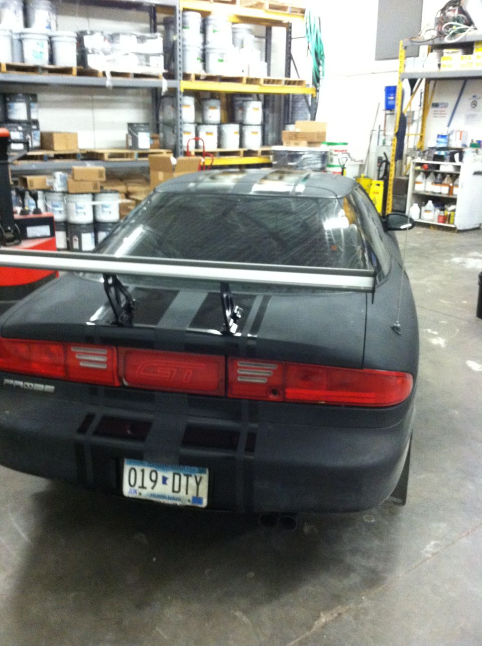 Rear view of black car with spoiler and racing stripes. License plate 019-DTY
