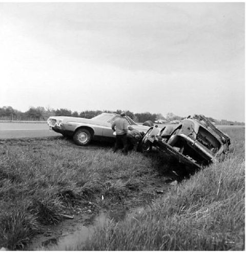 1971 Ford Ranchero - Two vehicles are wrecked in a ditch beside a road, one on its side.