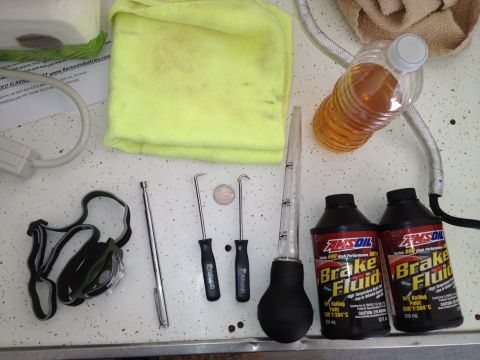 2013 Ford Mustang - Tools and supplies for automotive brake fluid maintenance are laid out on a speckled surface.