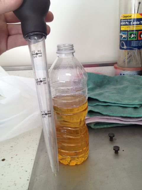 2013 Ford Mustang - A pipette is used to measure fluid from a plastic bottle, with tools and rags in the background.