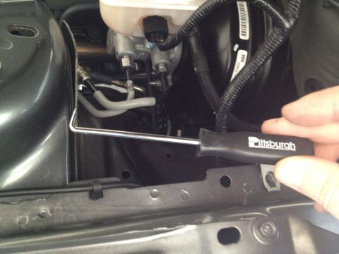 2013 Ford Mustang - Brake fluid reservoir and master cylinder assembly shown with a tool.