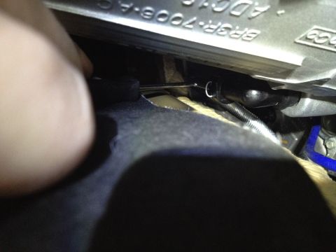 2013 Ford Mustang - A hand is shown working on a car's undercarriage, with visible text on a metal part.