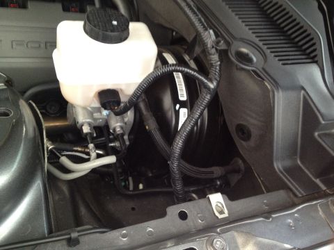 2013 Ford Mustang - The brake master cylinder and booster assembly are visible in the engine bay of a 2013 Ford Mustang.
