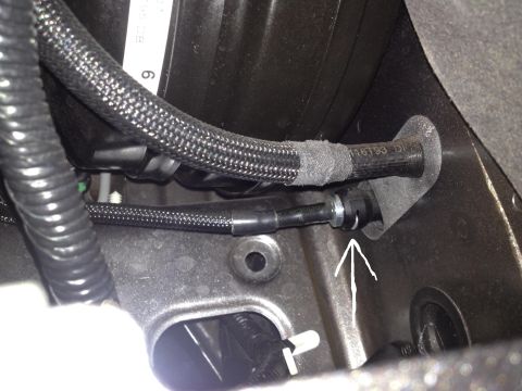 2013 Ford Mustang - A close-up view of automotive wiring and hoses within the engine bay, with an arrow indicating a specific connection.