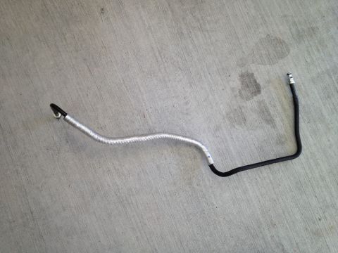 2013 Ford Mustang - A close-up view of a single automotive hose with protective shielding against a concrete background.