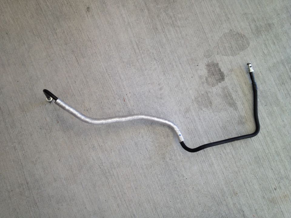 automotive hose with metal shielding and black rubber tubing, lying on concrete