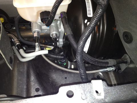 2013 Ford Mustang - Close-up view of the brake master cylinder and booster assembly, showing various hoses and lines.