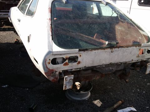2007 Ford F-250 - Rear view of a heavily rusted white car, likely a project vehicle or parts car.