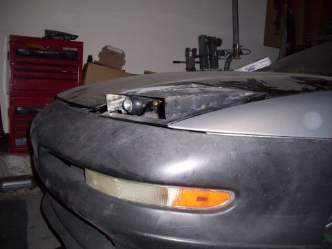1995 Ford Probe - Front end of a 1995 Ford Probe with the pop-up headlight mechanism exposed for work.