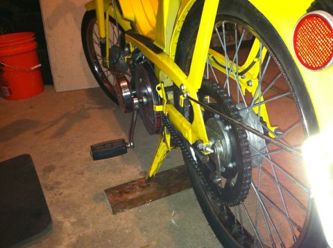 1981 Garelli Rally Sport - Close-up view of the rear wheel, chain, and pedals of a yellow moped.
